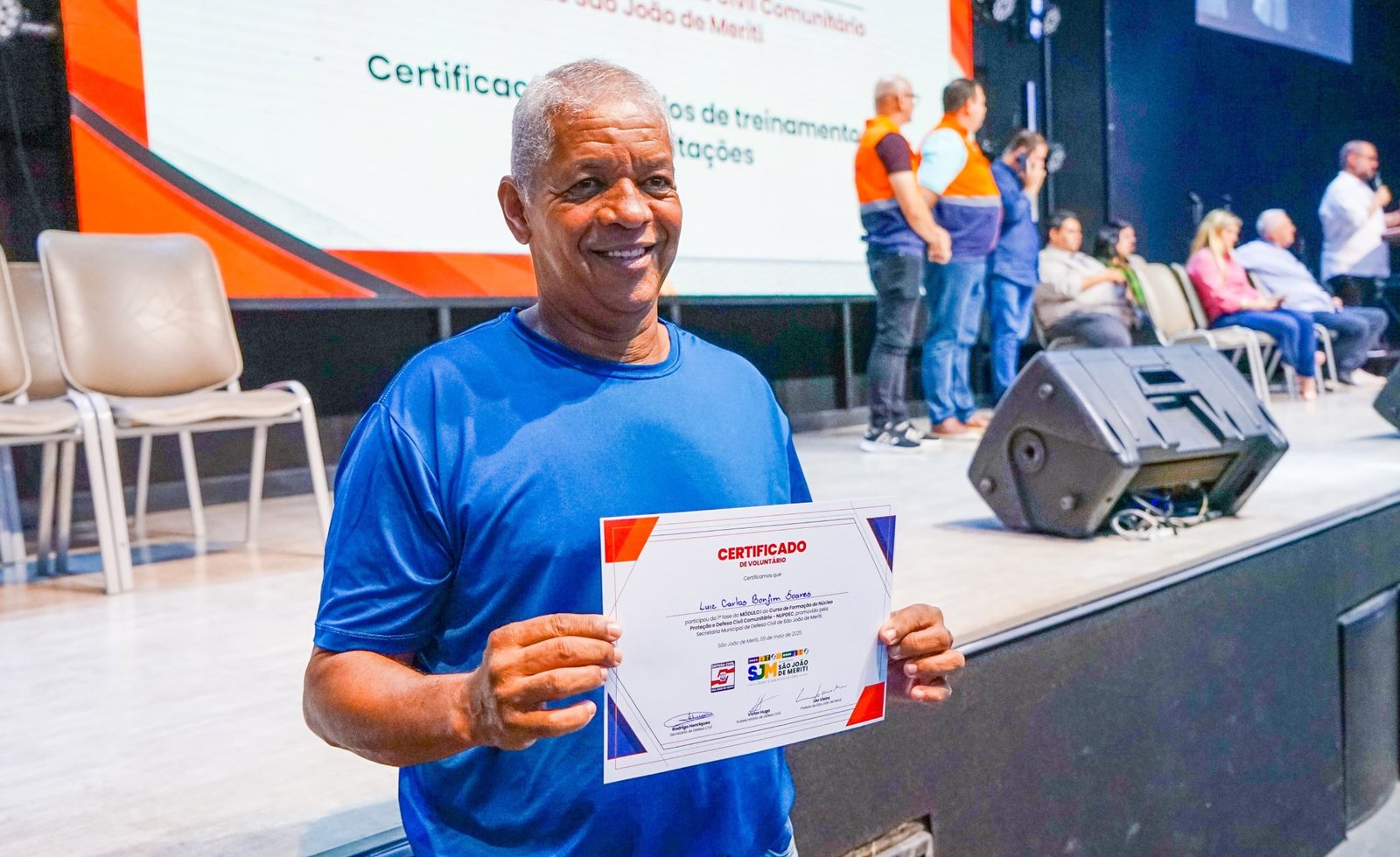 Na noite desta terça-feira (13/05), a Defesa Civil de São João de Meriti realizou uma cerimônia marcante de certificação dos voluntários capacitados no primeiro módulo de formação dos Núcleos Comunitários de Proteção e Defesa Civil (NUPDECs). O evento também marcou o credenciamento de 41 novas instituições religiosas que passarão a integrar a rede de apoio à população em casos de emergência. O prefeito Léo Vieira destacou a importância da preparação e da prevenção. “A Defesa Civil geralmente é lembrada quando acontece, infelizmente, algum desastre. O que estamos fazendo em nosso município é preparar as pessoas, orientar para a prevenção. Quando houver um momento adverso, como um alagamento ou um deslizamento de encosta, é essencial saber como dar os primeiros passos para se proteger e proteger outras pessoas”.